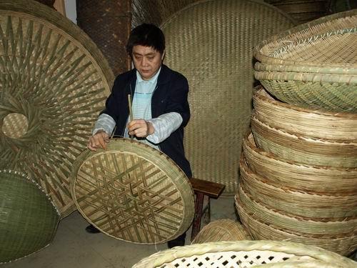 陈德义在农贸市场租赁的门市内利用销售闲暇制作竹簸箕.